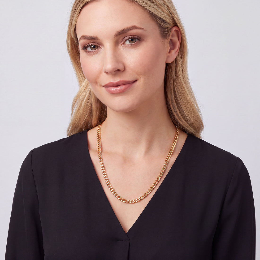 Blondīne valkā apzeltītu bruņuveida ķēdīti pie lina krekla