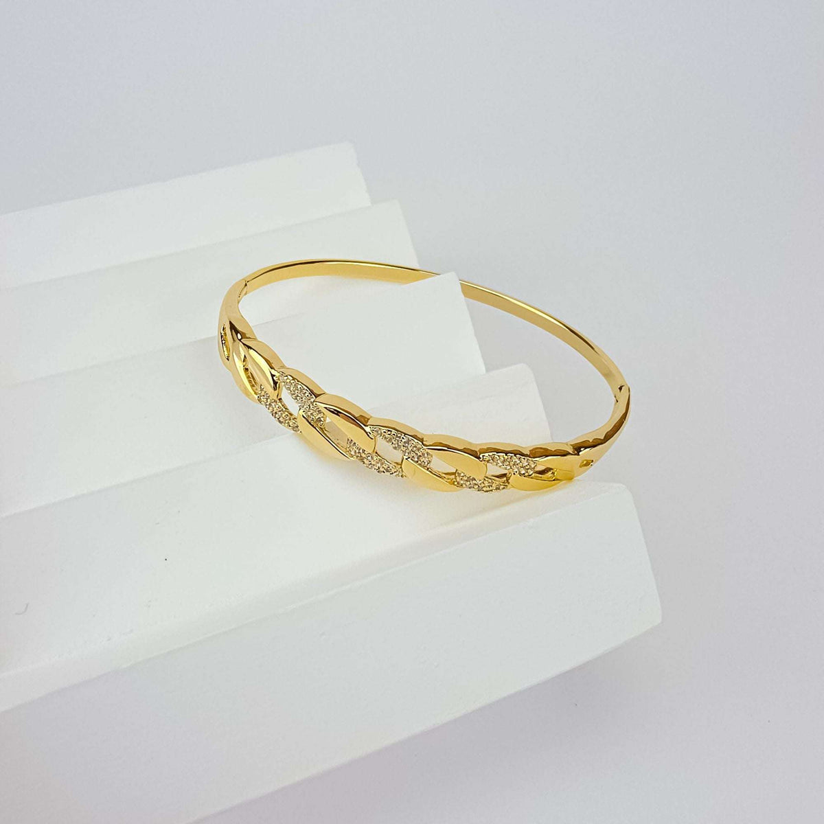 Apzeltīta cietā bangle rokassprādze ar ķēdes posmu rakstu un dzirkstošiem cirkoniem uz balta paaugstinājuma