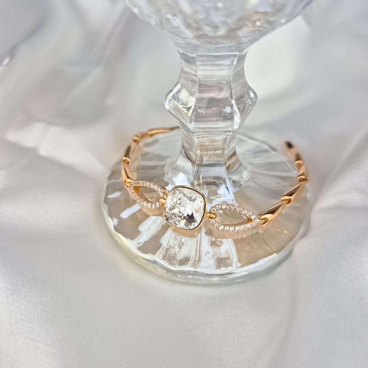 Aproce ar mirdzošu Swarovski kristālu uz stikla paliktņa, redzami cirkoniem rotātie posmi